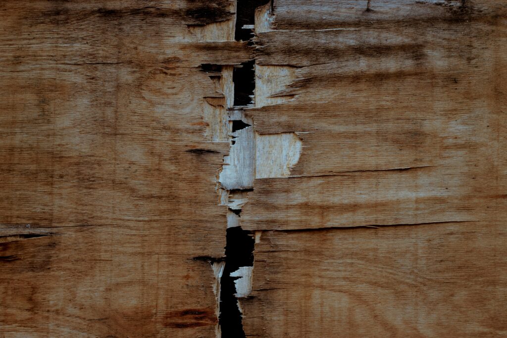 Close-up of a cracked rustic wooden surface with visible texture and grunge elements.